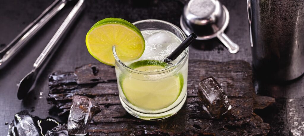 glass of dawa with bar utensils. typical drink from brazil, made with lemon, on a black table